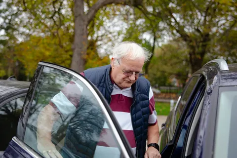 Un signore anziano apre la portiera di un'auto per salire